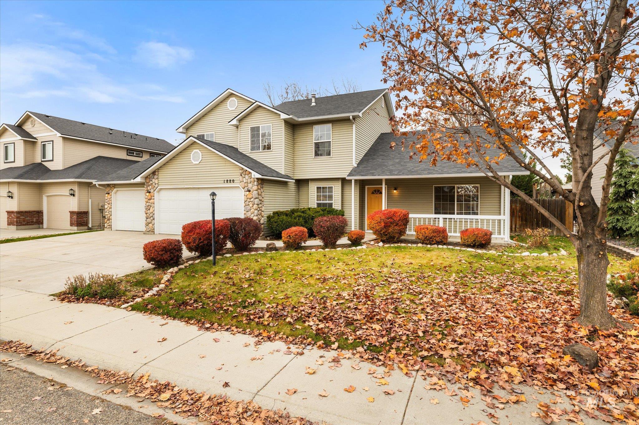 Traditional-style home with concrete driveway, covered porch, stone siding, a shingled roof, and an attached garage