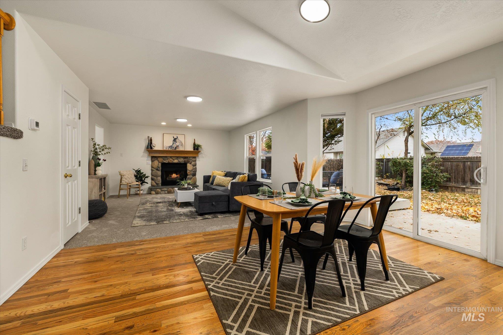 Dining space with a stone fireplace, recessed lighting, vaulted ceiling, and light wood-type flooring