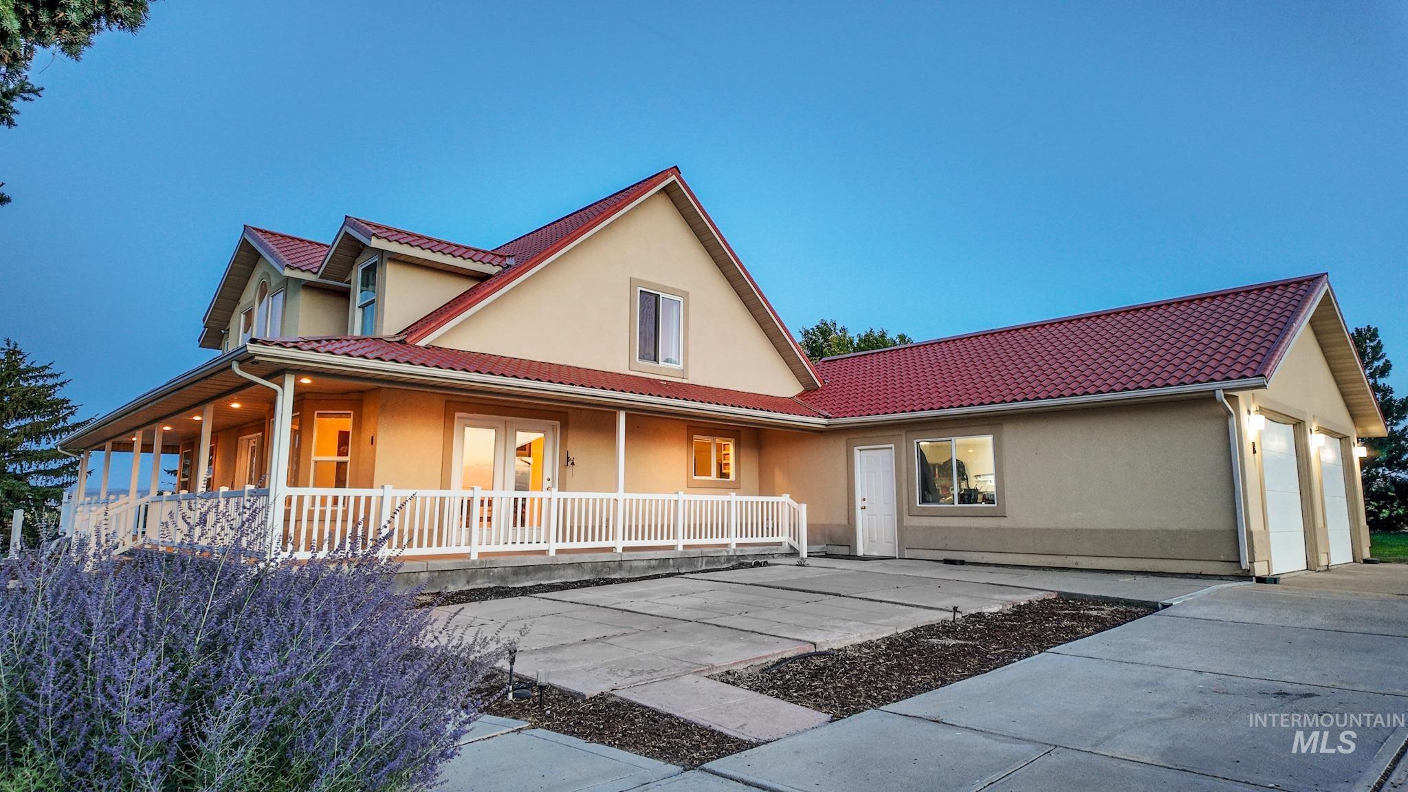Farmhouse featuring stucco siding, a porch, a tiled roof, a garage, and concrete driveway