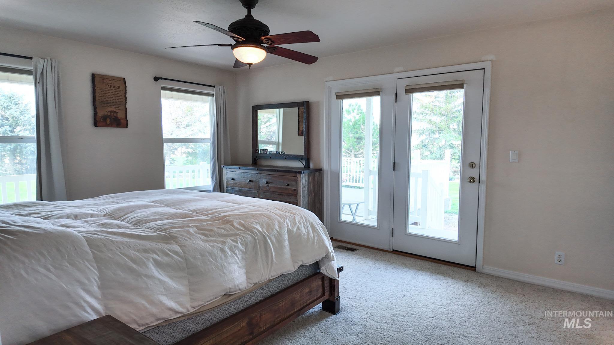 Bedroom with access to outside, carpet flooring, and a ceiling fan