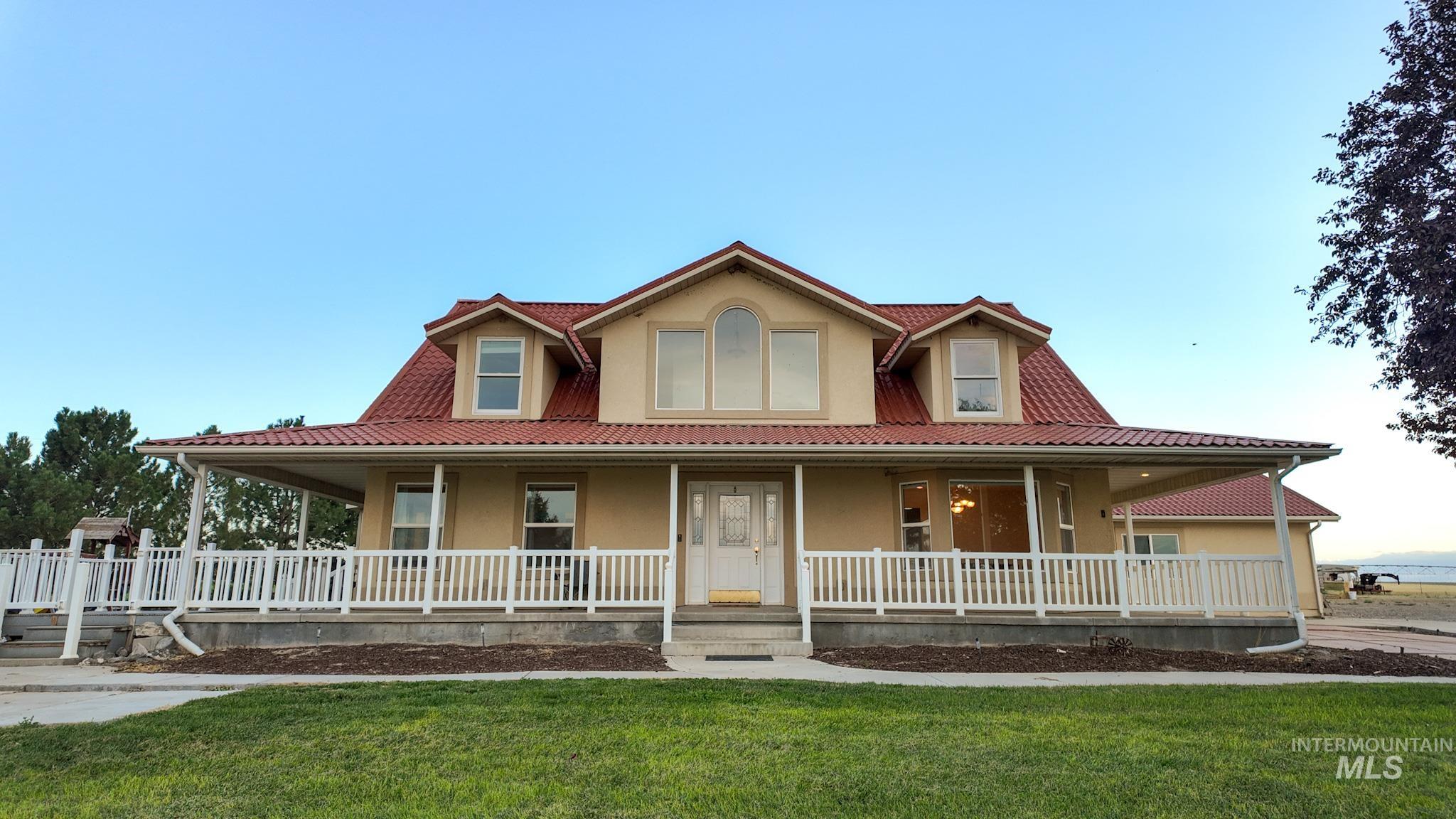 Farmhouse-style home featuring stucco siding, a porch, and a front yard