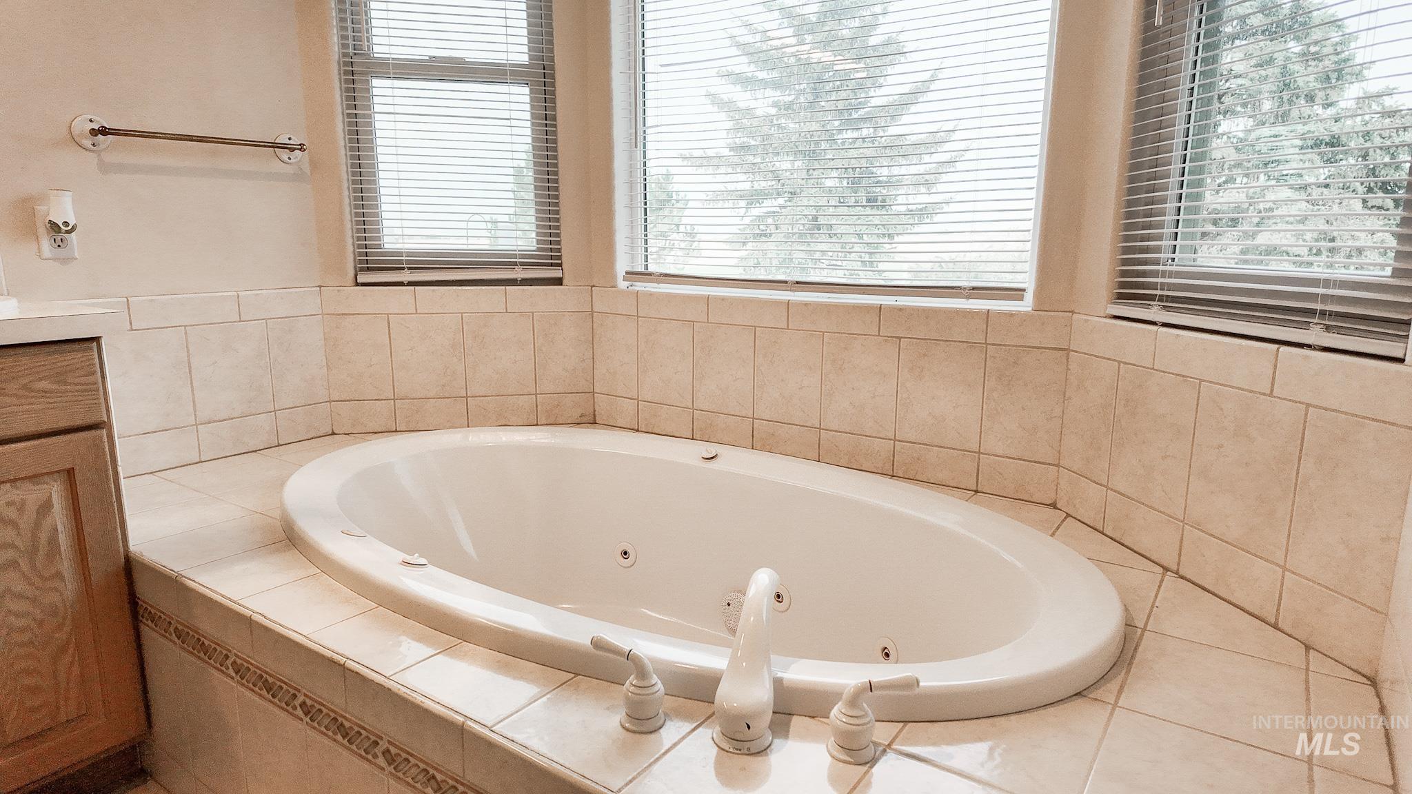Full bathroom with a whirlpool tub, healthy amount of natural light, and vanity
