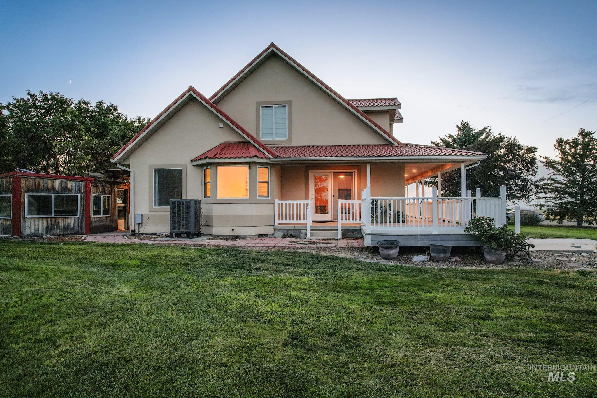 View of front of property with a lawn, stucco siding, a tiled roof, and a porch