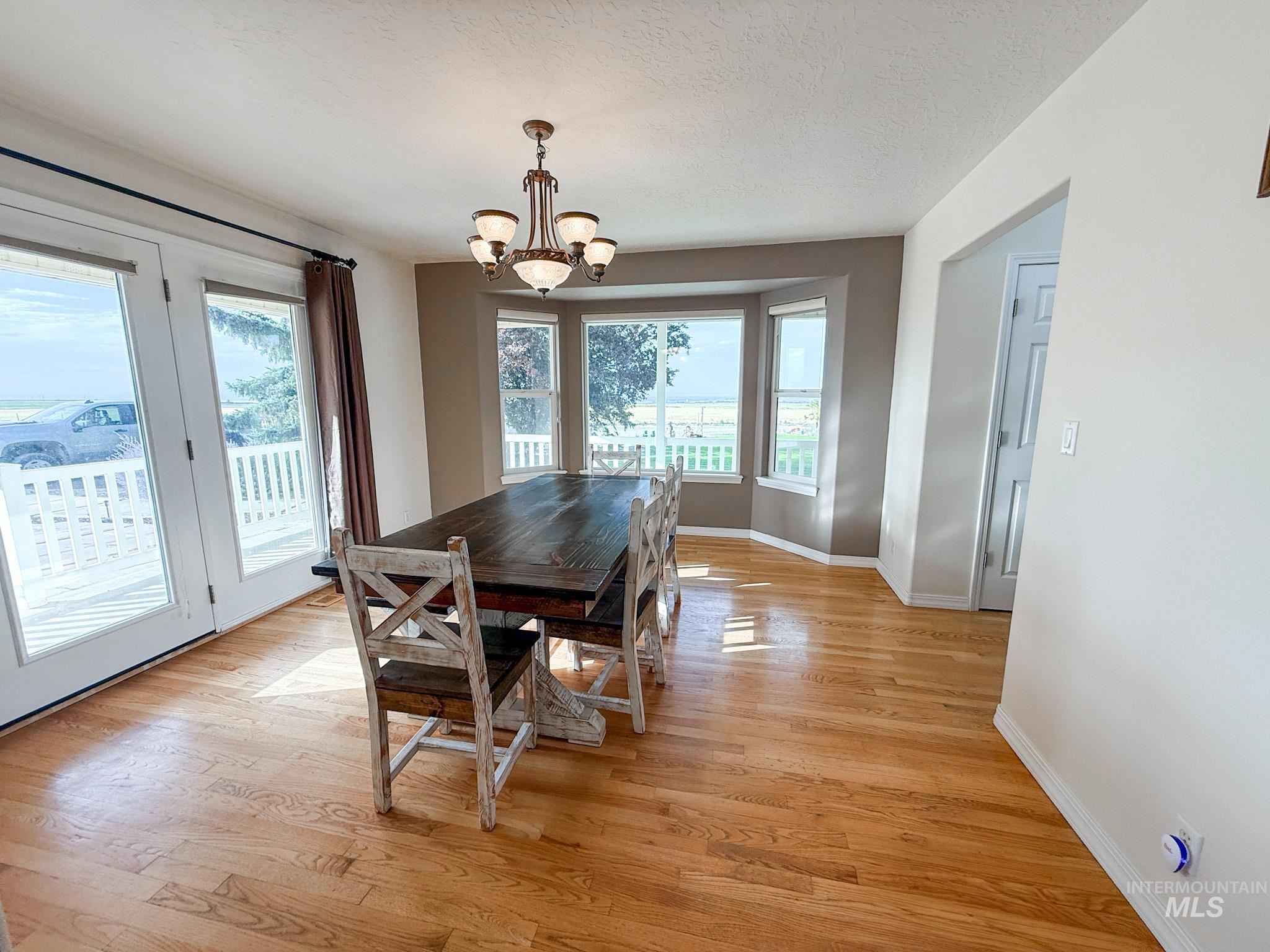 Dining space with light wood-type flooring, a chandelier, and a textured ceiling