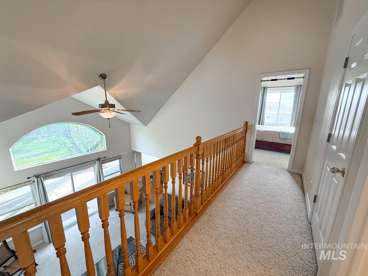 Hall featuring high vaulted ceiling, carpet floors, and an upstairs landing