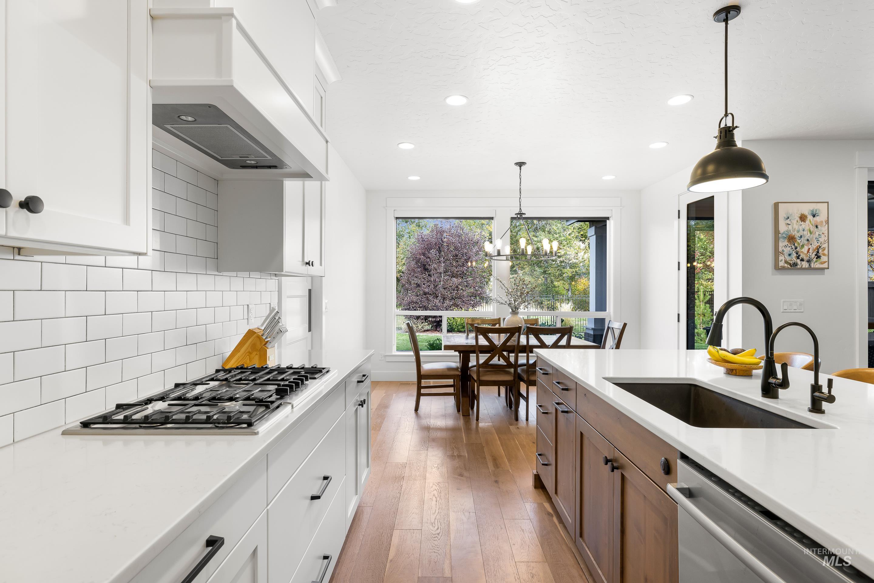 Kitchen featuring hanging light fixtures, white cabinets, light wood-type flooring, recessed lighting, and a textured ceiling