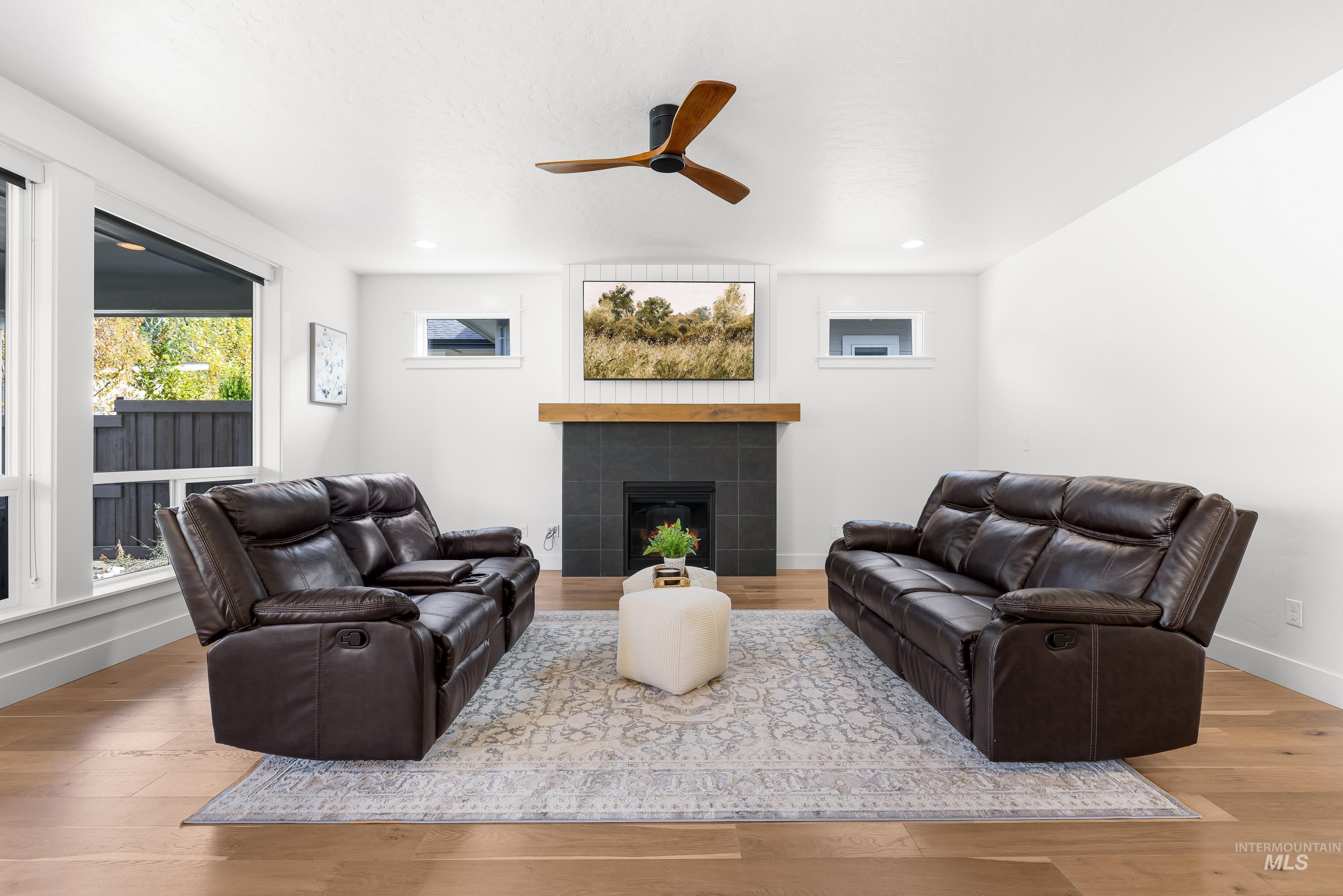 Living room with light wood-style floors, a fireplace, and a ceiling fan