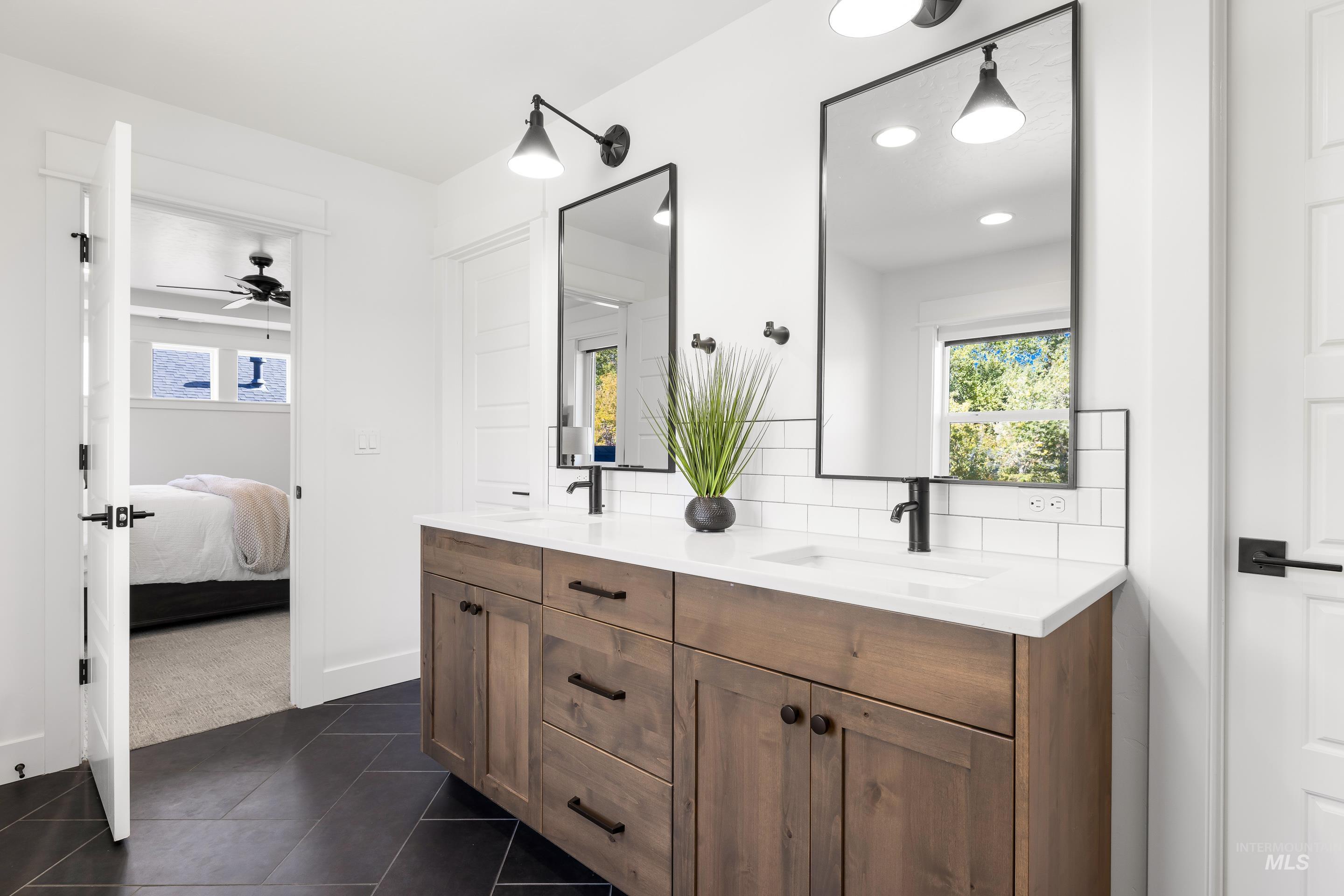 Bathroom with plenty of natural light, double vanity, dark tile patterned floors, connected bathroom, and recessed lighting