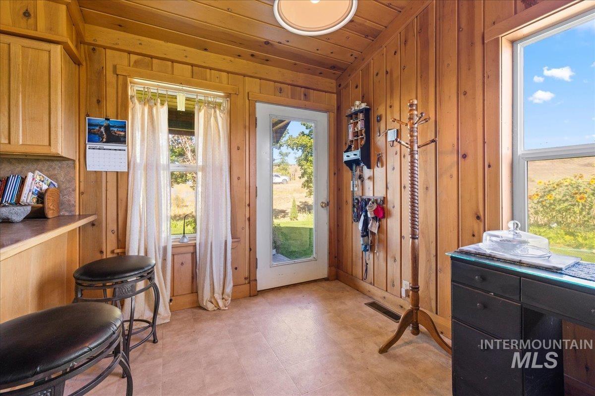 Entryway with tile patterned floors, wooden walls, and wood ceiling