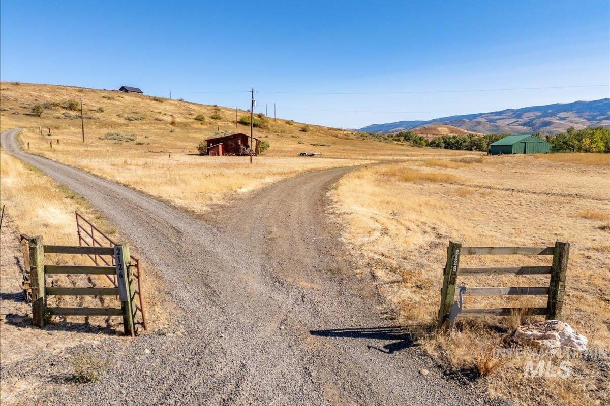 View of street featuring a view of countryside, a mountain view, and a gated entry