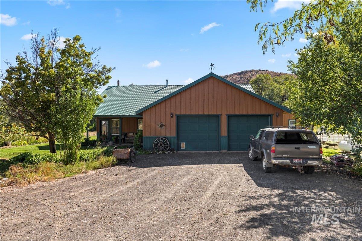 View of front facade with driveway, a metal roof, a garage, and covered porch