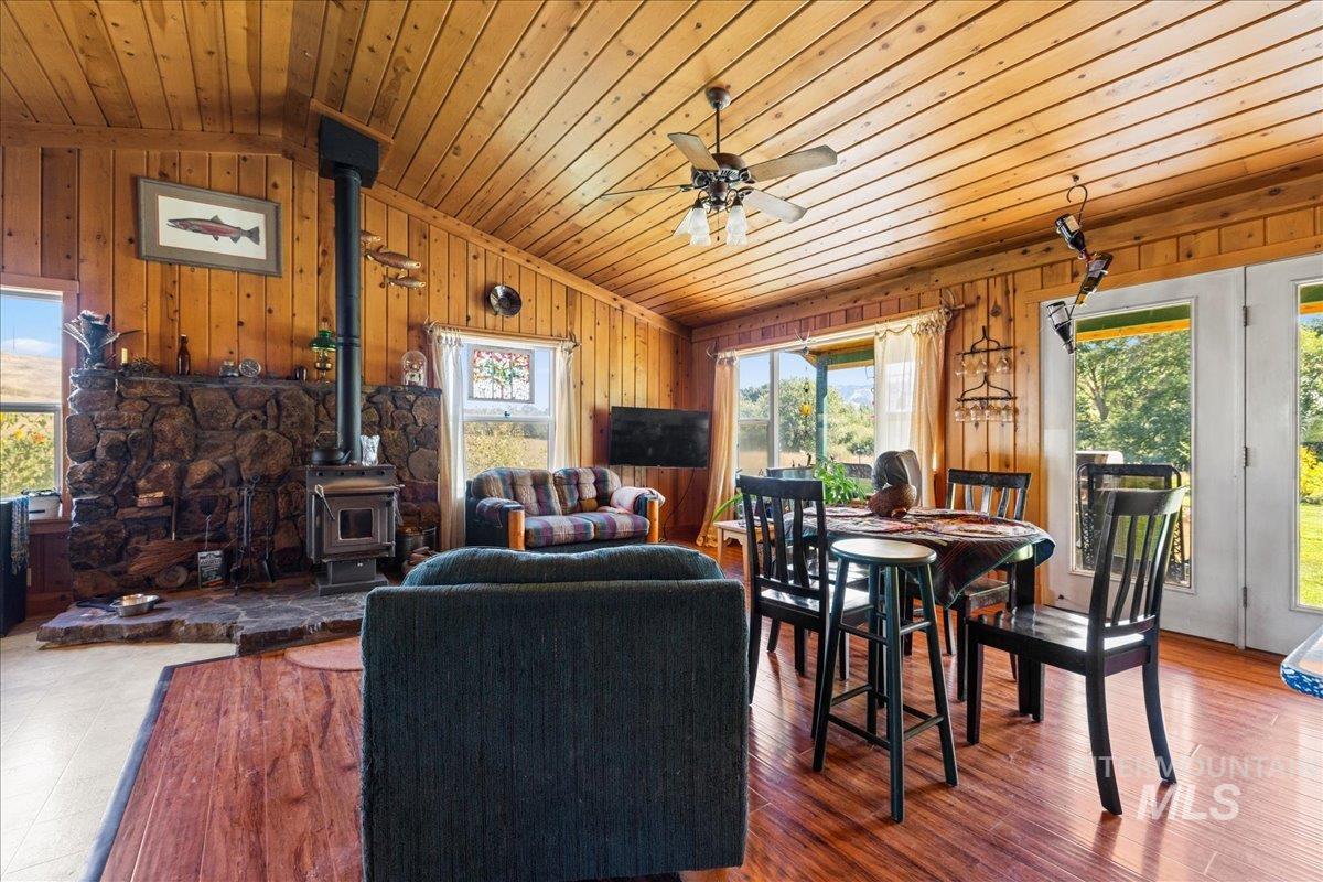 Living area featuring a wood stove, vaulted ceiling, wood finished floors, wooden walls, and wooden ceiling
