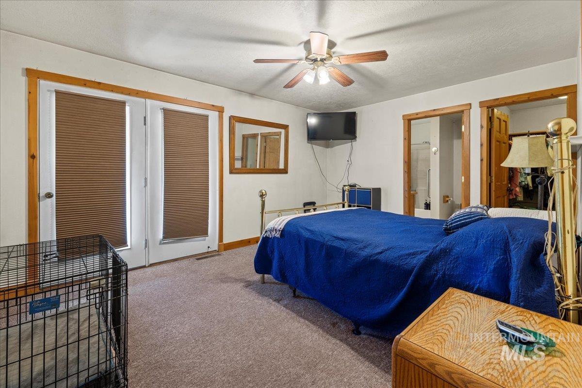 Carpeted bedroom featuring a ceiling fan and a textured ceiling