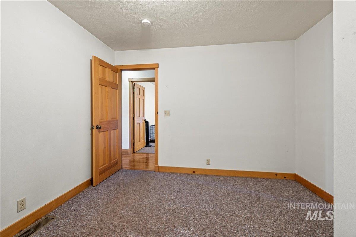 Carpeted empty room featuring a textured ceiling and baseboards