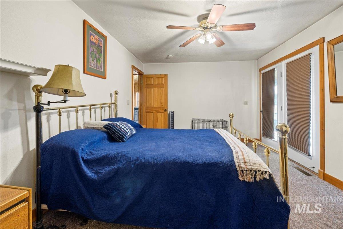 Carpeted bedroom with ceiling fan and a textured ceiling