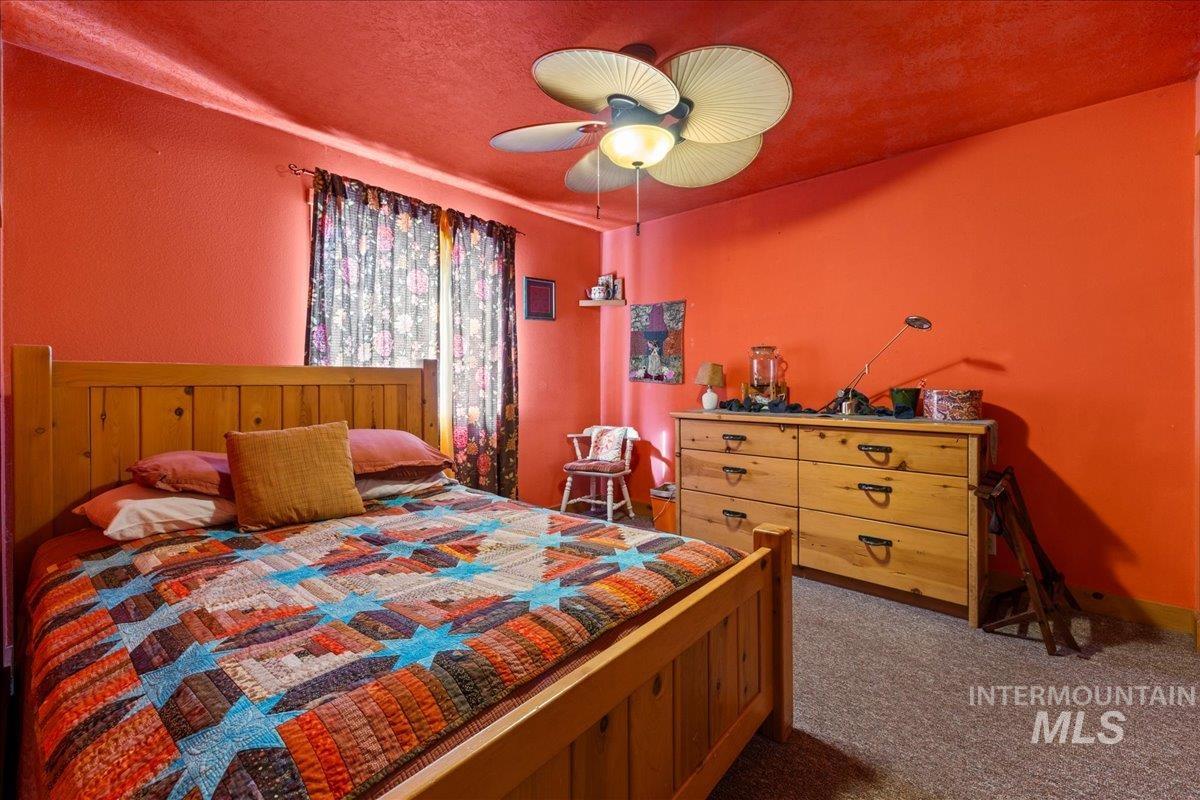 Bedroom with dark carpet, a ceiling fan, and a textured ceiling