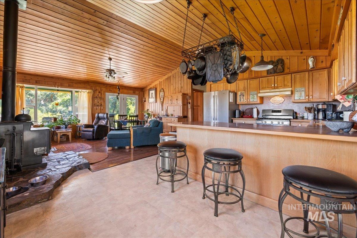 Kitchen with a wood stove, a breakfast bar, a peninsula, wood walls, and stainless steel appliances