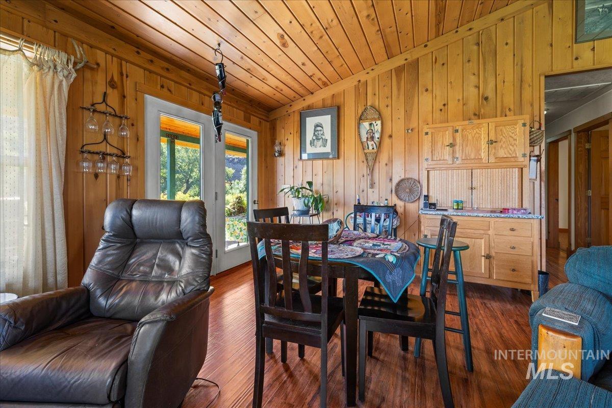 Dining area featuring dark wood finished floors, vaulted ceiling, wood walls, and wooden ceiling