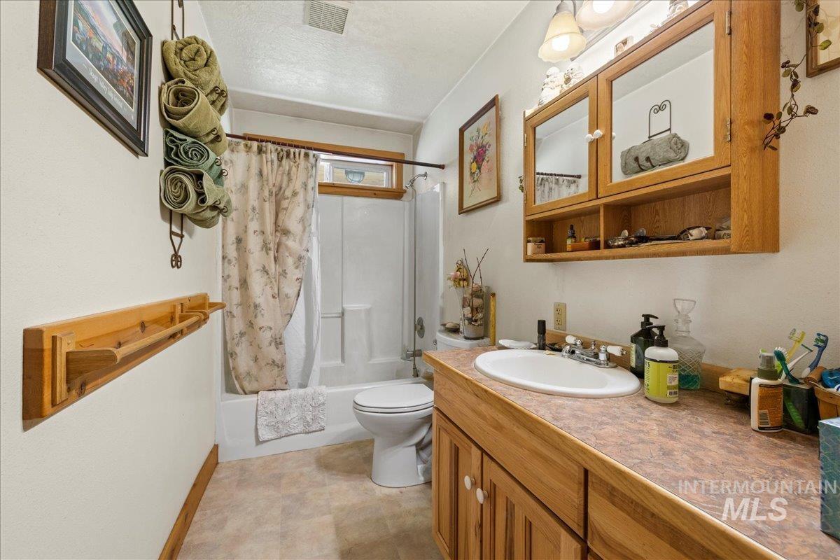 Bathroom with shower / bath combo, vanity, and a textured ceiling