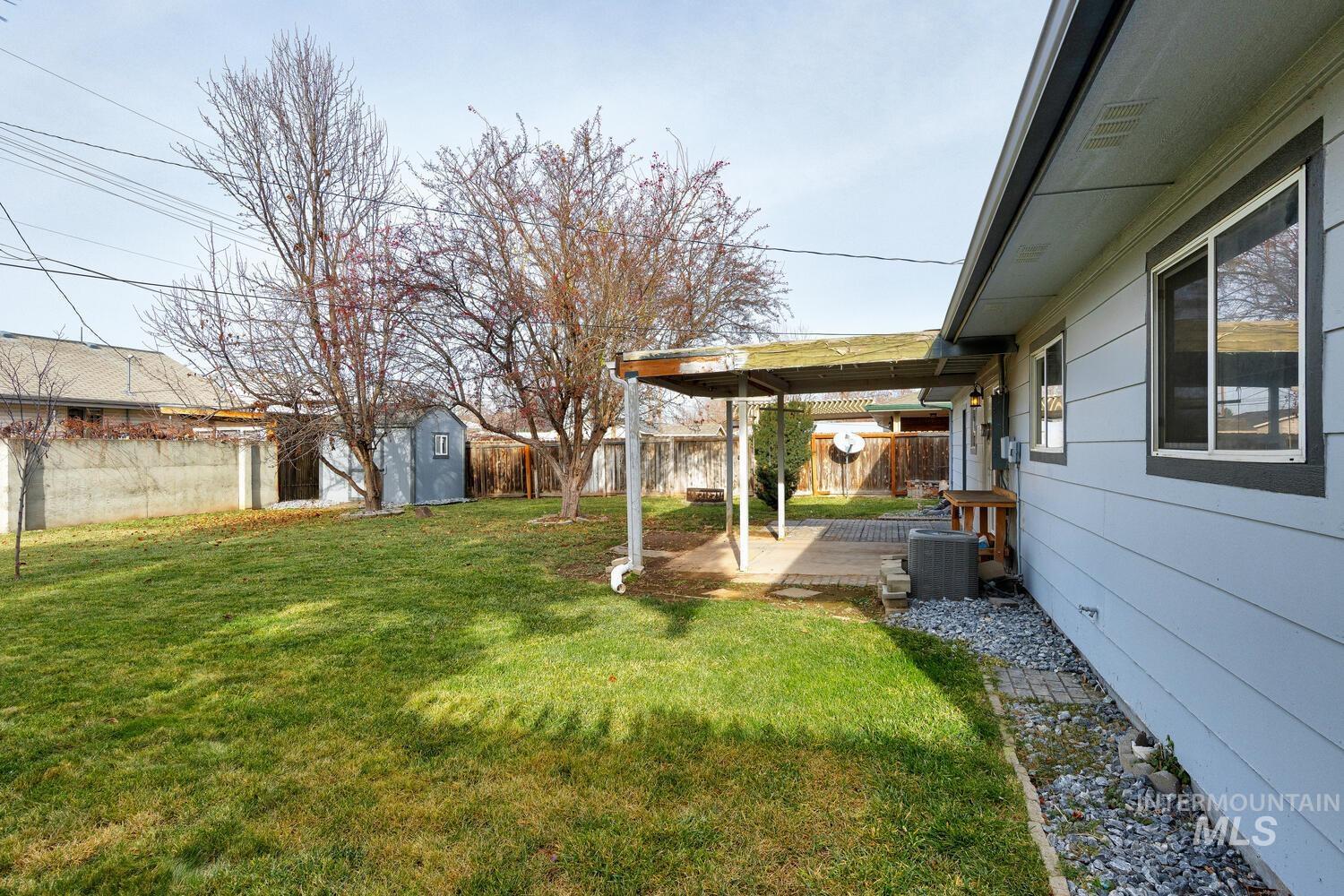 Fenced backyard with a storage shed and a patio area