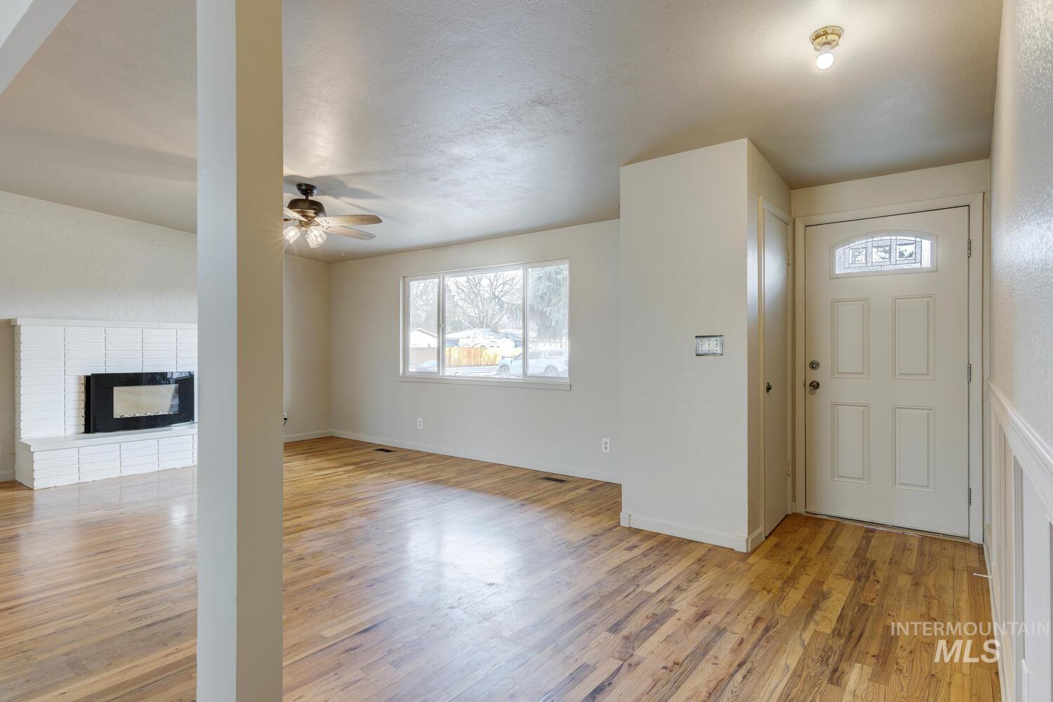 Entryway featuring light wood-type flooring, a brick fireplace, and a ceiling fan