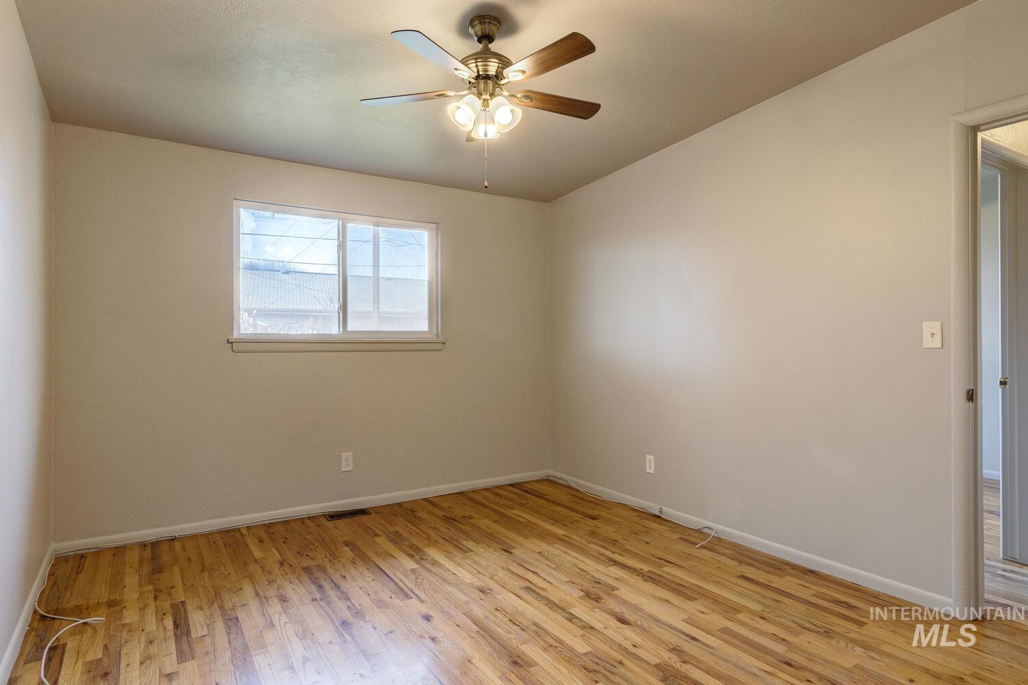 Empty room featuring light wood-style flooring and ceiling fan
