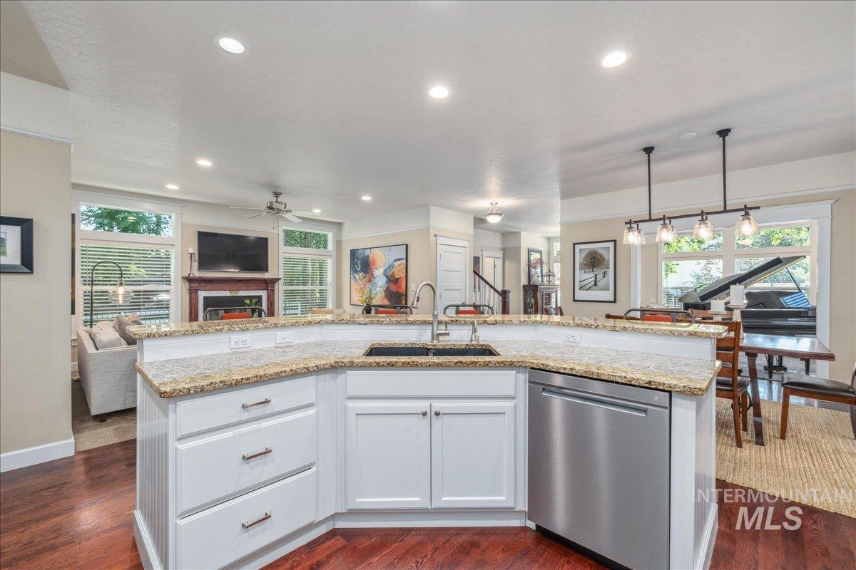Kitchen featuring open floor plan, a center island with sink, dishwasher, light stone counters, and recessed lighting