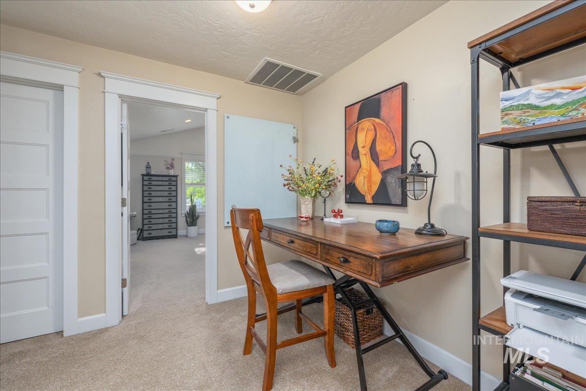 Office area with light colored carpet and a textured ceiling