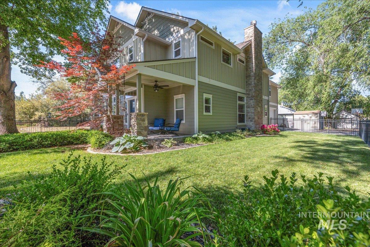 Rear view of house with a ceiling fan, board and batten siding, a chimney, and a patio area