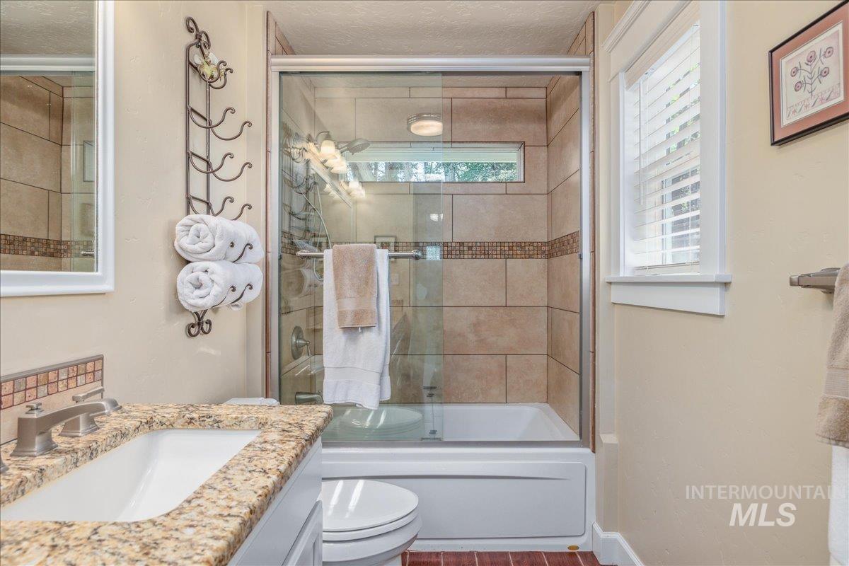 Full bath featuring bath / shower combo with glass door, vanity, and a textured ceiling