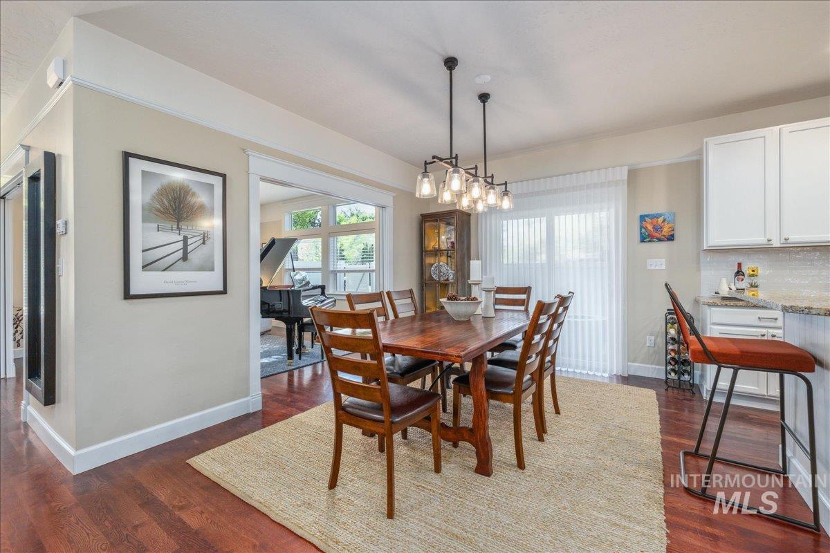 Dining space with dark wood-style floors and baseboards
