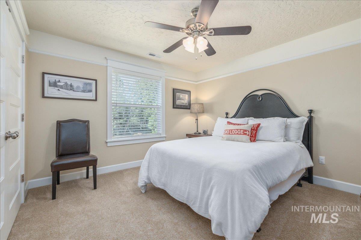 Bedroom featuring light colored carpet, a textured ceiling, and ceiling fan