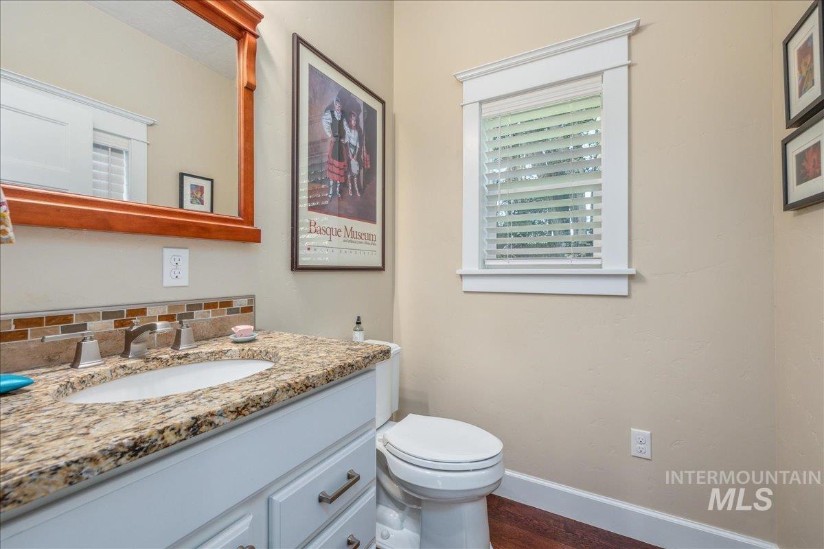 Half bath with vanity, tasteful backsplash, and dark wood-style floors