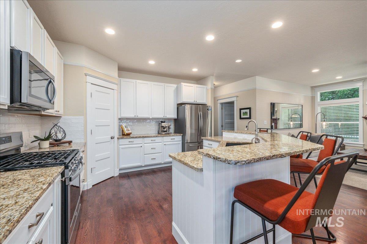 Kitchen with appliances with stainless steel finishes, a kitchen bar, a spacious island, white cabinets, and recessed lighting