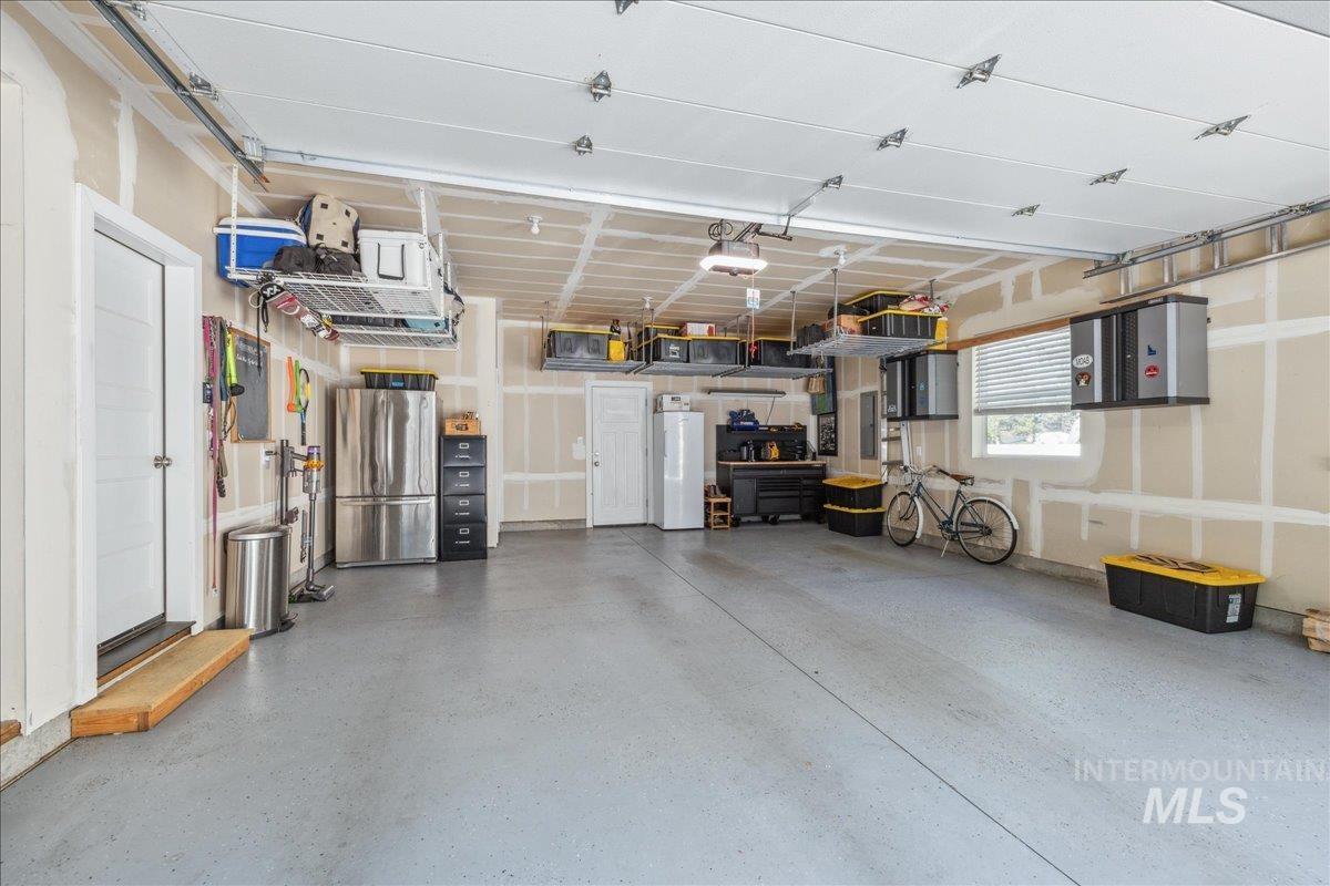 Garage featuring freestanding refrigerator, white refrigerator, and a garage door opener