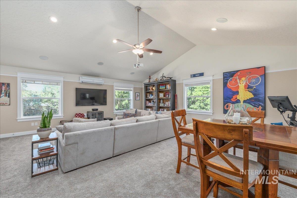 Living room with light colored carpet, high vaulted ceiling, a ceiling fan, and a wall mounted air conditioner