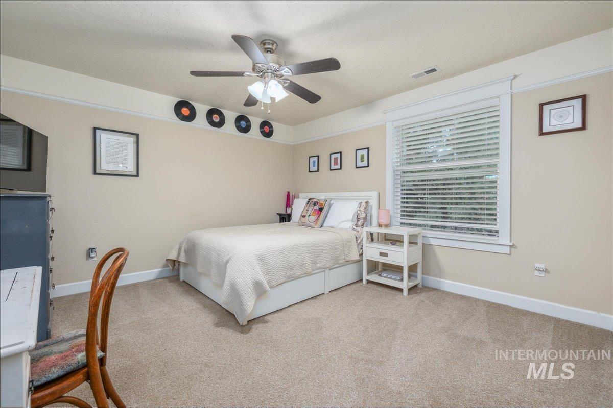 Carpeted bedroom with a ceiling fan and a textured ceiling