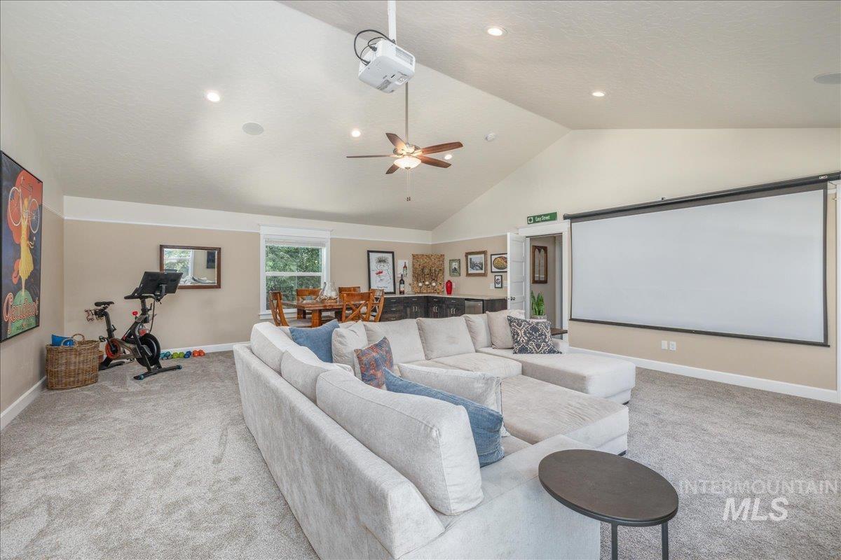 Cinema featuring high vaulted ceiling, carpet floors, ceiling fan, and a textured ceiling
