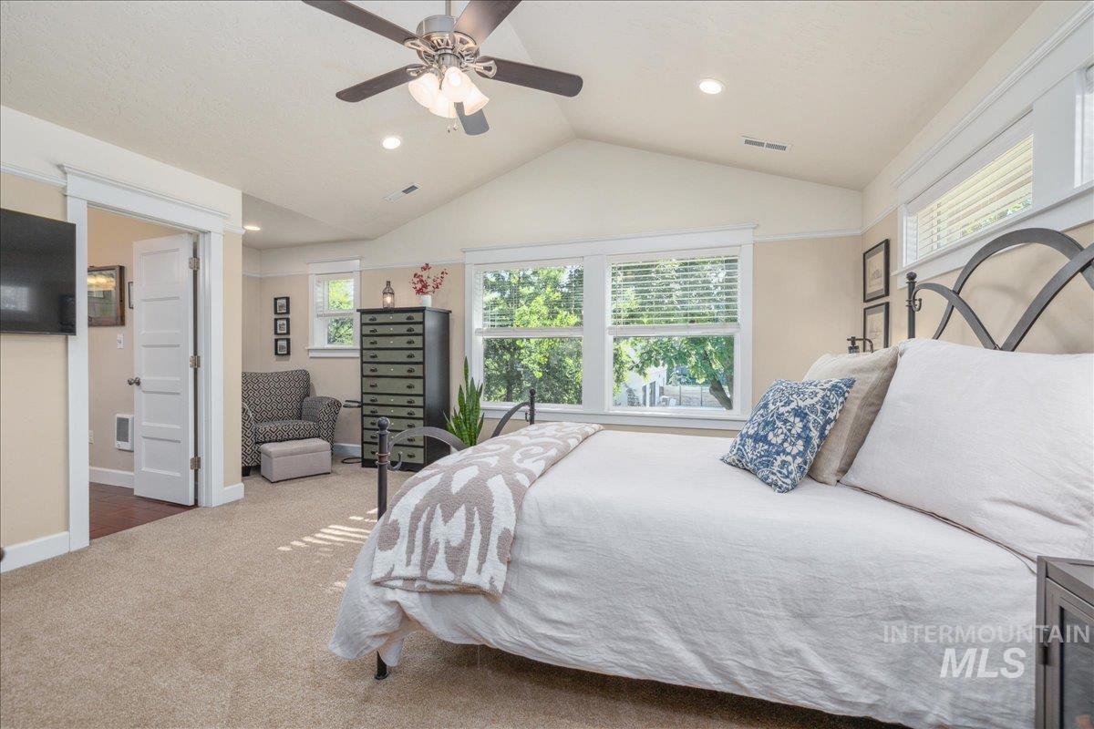 Carpeted bedroom featuring ceiling fan, vaulted ceiling, and recessed lighting
