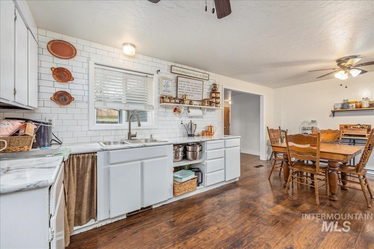 Kitchen with open shelves, ceiling fan, white cabinetry, decorative backsplash, and dark wood-style floors