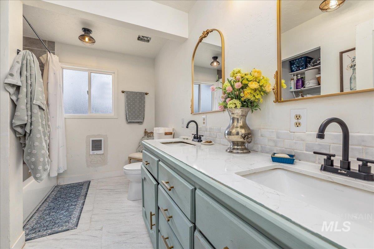 Bathroom featuring double vanity and shower / bath combination with curtain