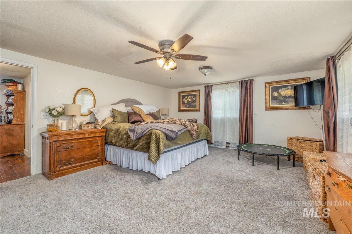 Carpeted bedroom featuring a textured ceiling and ceiling fan