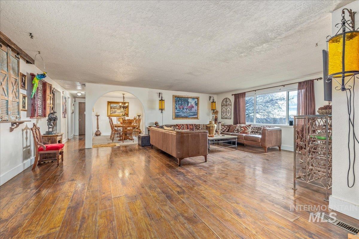 Living area with arched walkways, wood-type flooring, and a textured ceiling