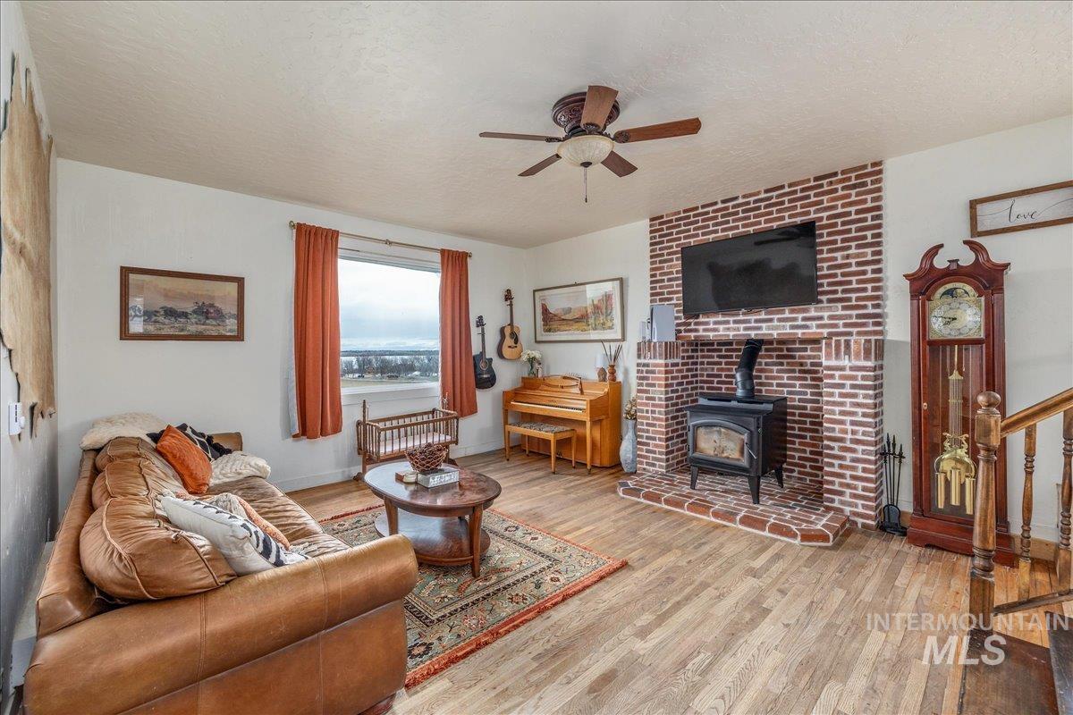 Living area featuring a textured ceiling, light wood-type flooring, a wood stove, and ceiling fan