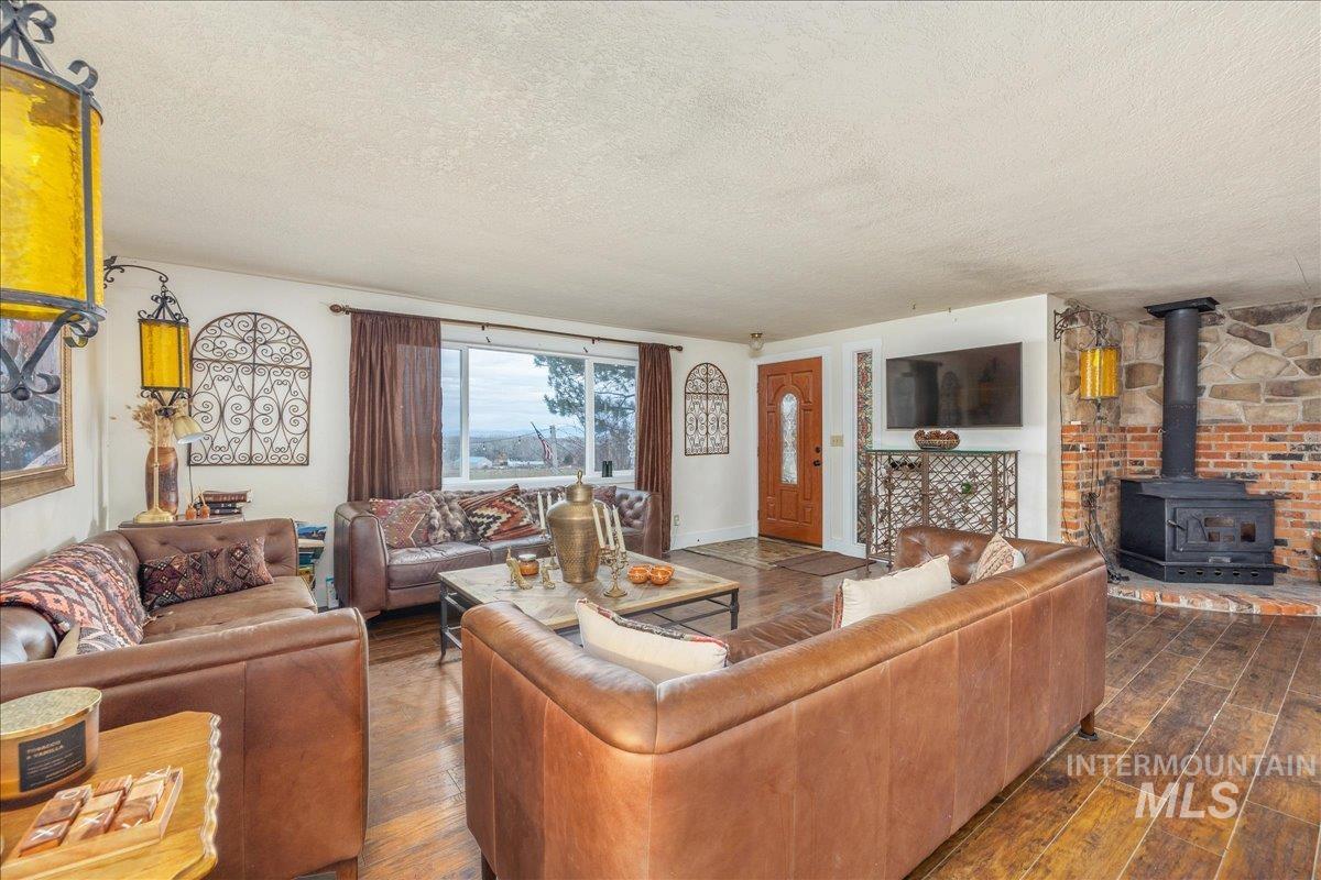 Living area with a wood stove, a textured ceiling, and dark wood-style floors