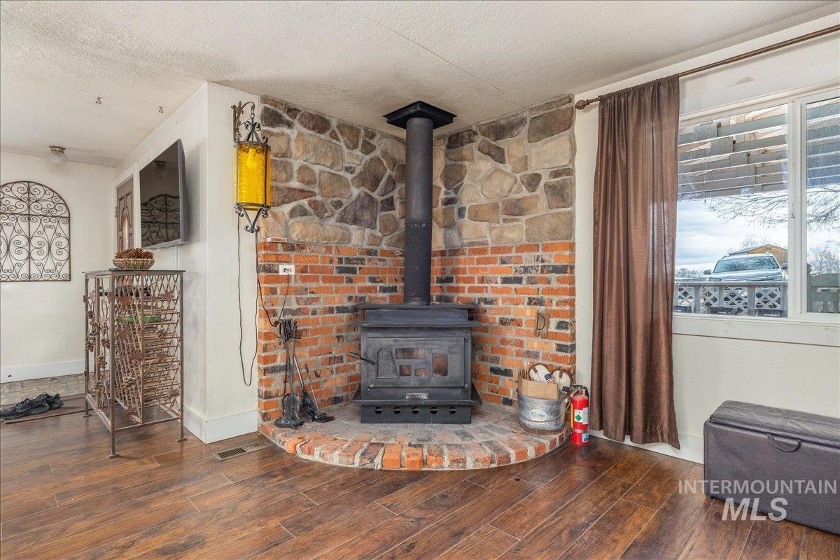 Detailed view of wood finished floors, a textured ceiling, and a wood stove