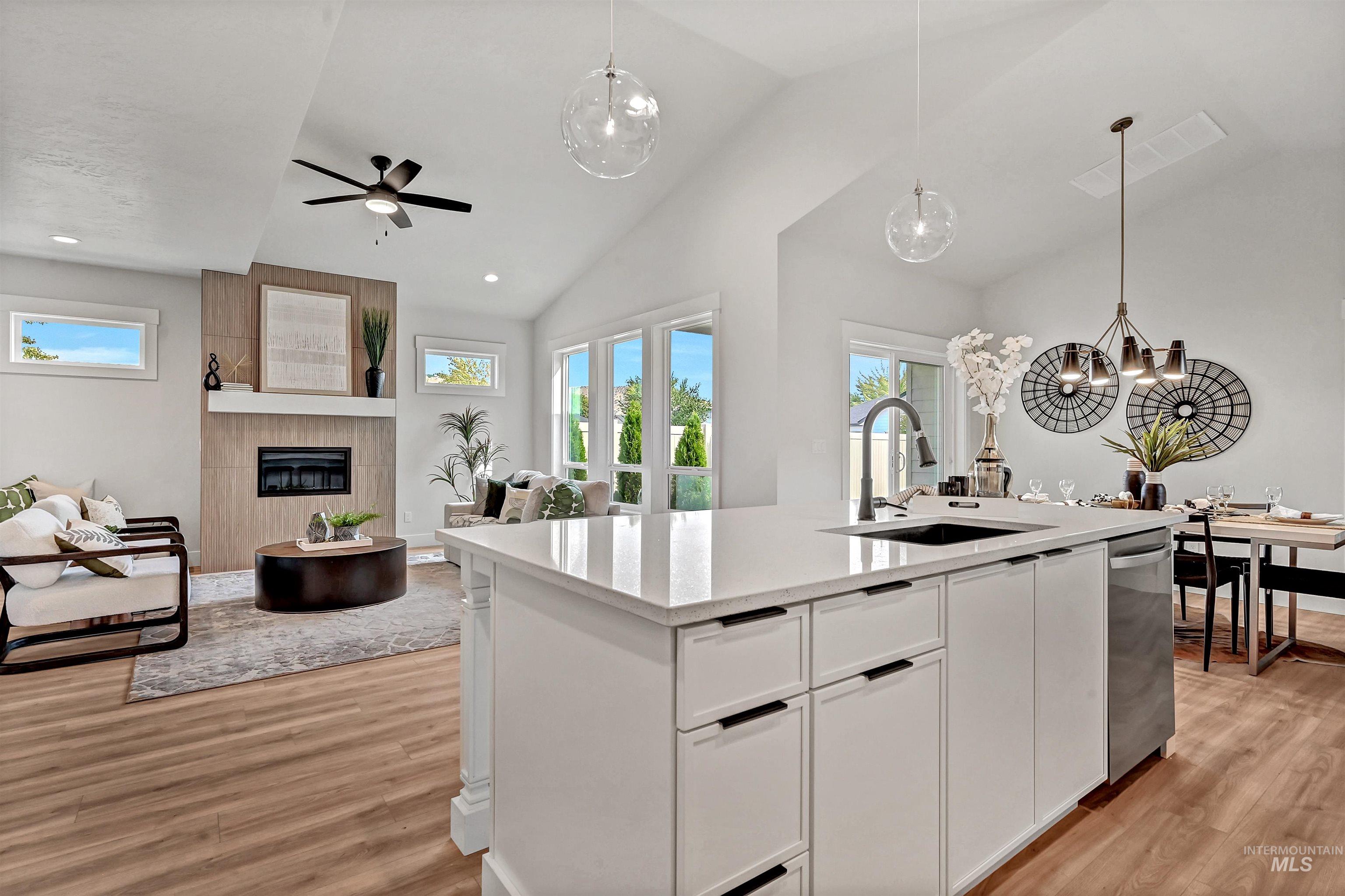 Kitchen featuring white cabinetry, hanging light fixtures, vaulted ceiling, open floor plan, and light wood-style floors