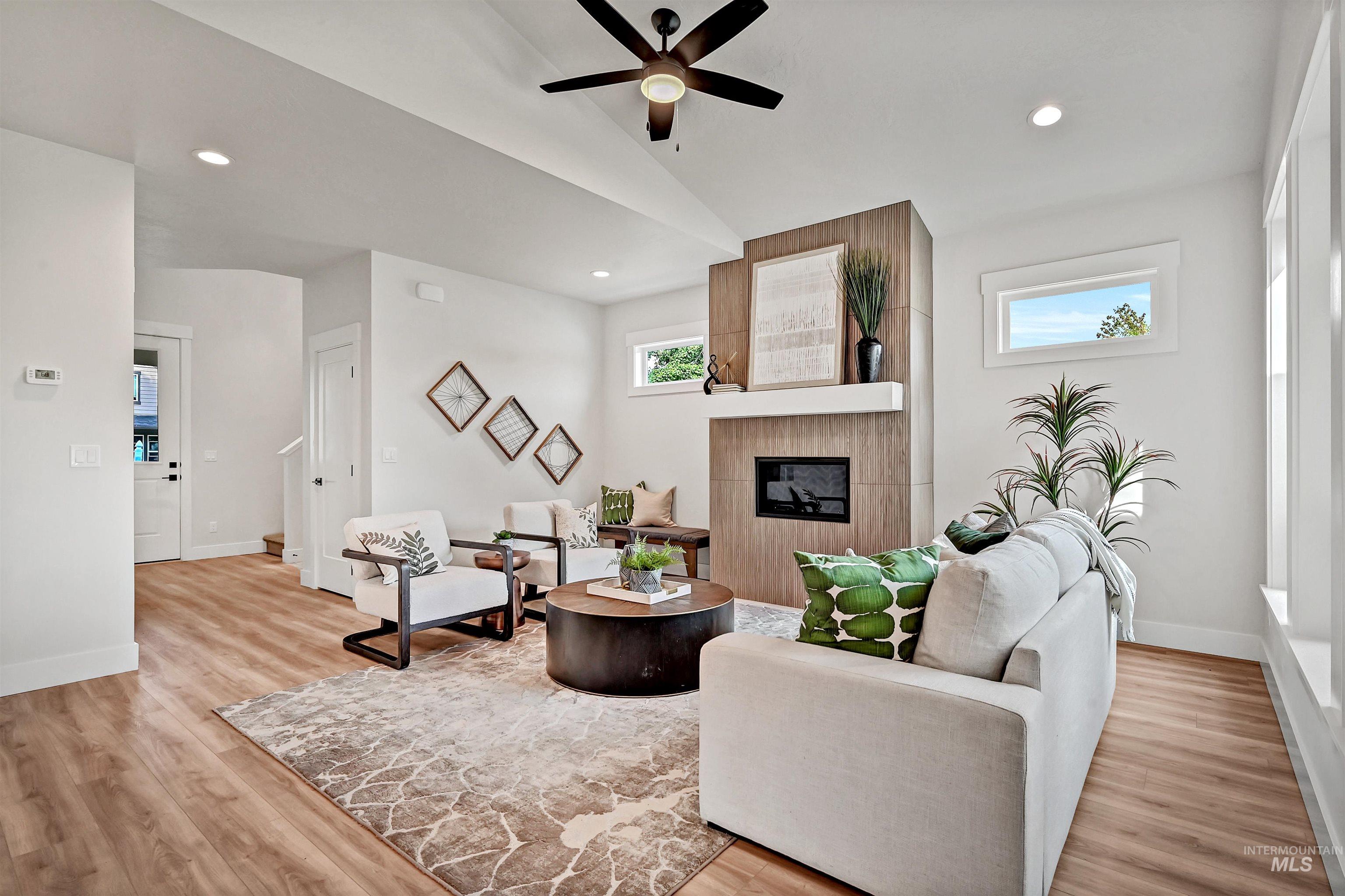 Living area featuring recessed lighting, lofted ceiling, a tile fireplace, light wood-style floors, and a ceiling fan