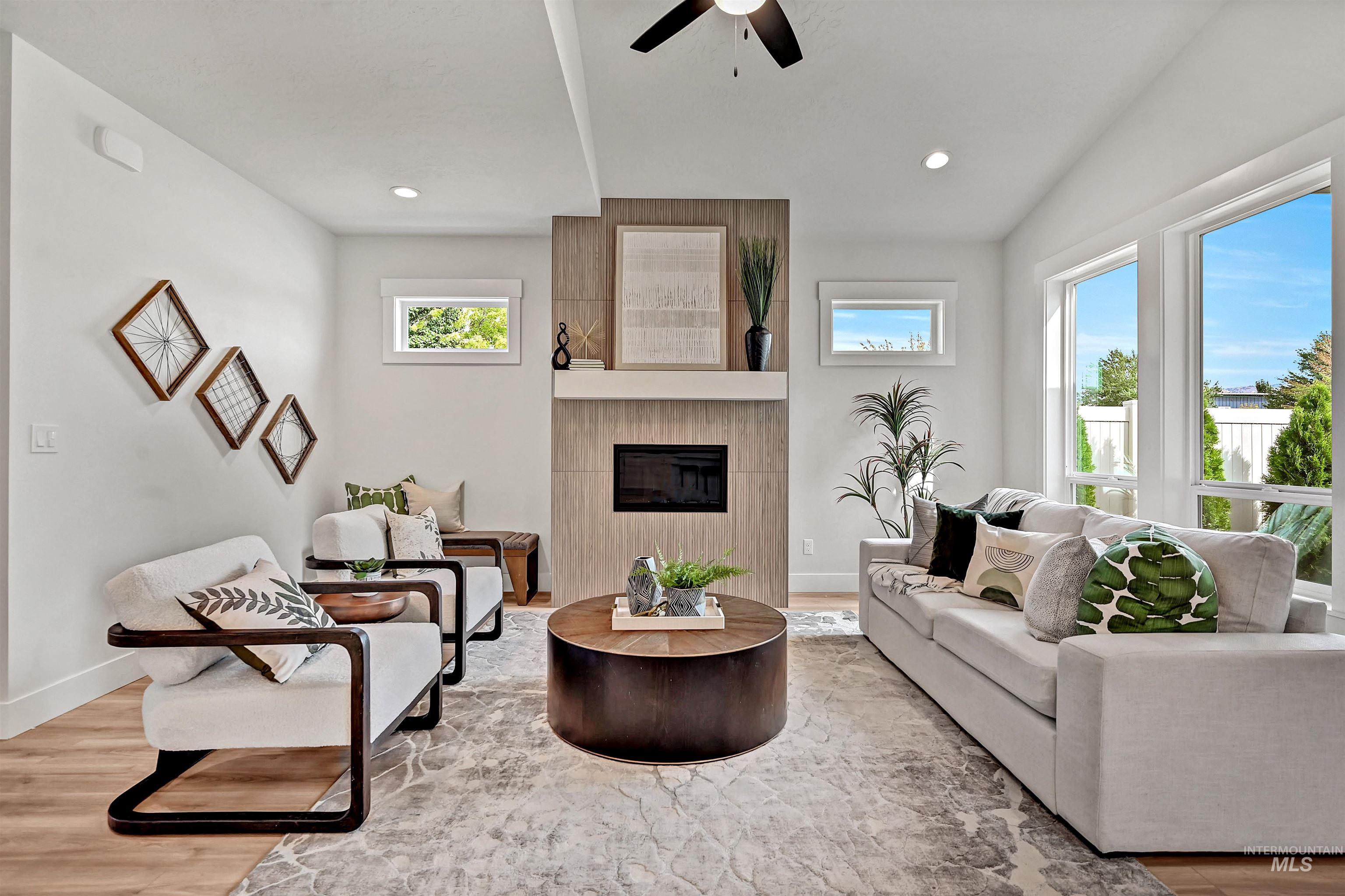 Living area with light wood-type flooring, a tile fireplace, ceiling fan, and recessed lighting