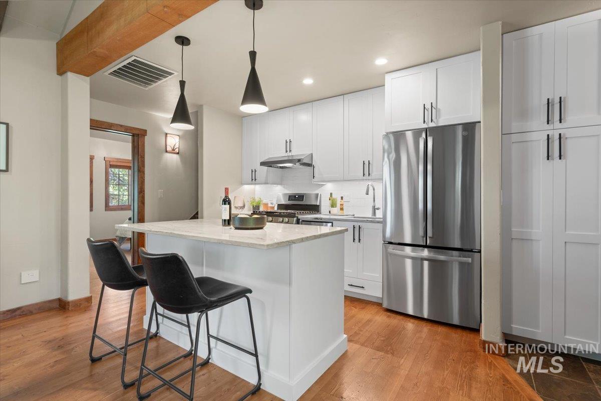 Modern kitchen featuring white shaker cabinetry and a central island with countertop seating
